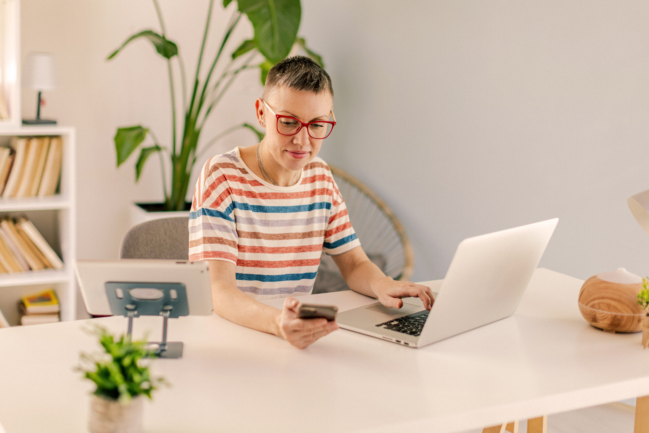 Person using phone with laptop.