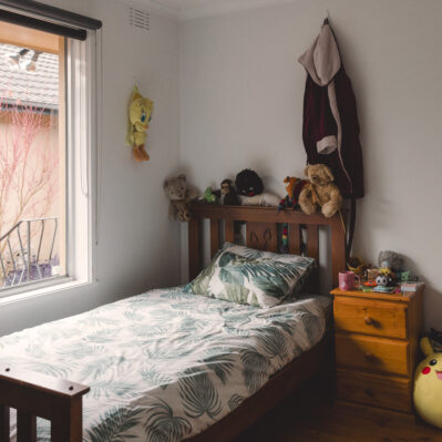 On top of the single bed and timber bedside table are a number of soft toys and cute knick-knacks.