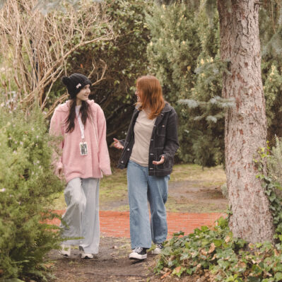 A resident and her support worker chatting as they walk through the garden.