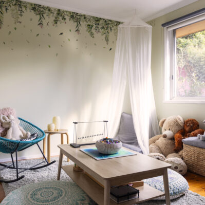 A cosy room with chairs and floor pillows around a coffee table, including a selection of sensory objects and plush toys.