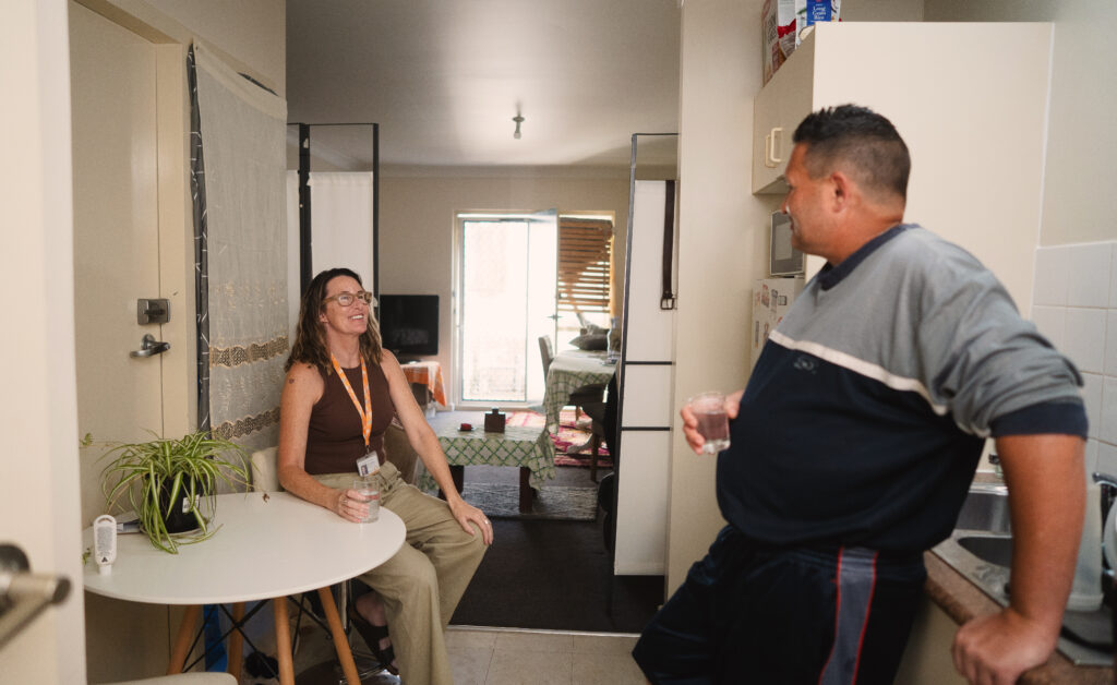Natalie, Lived Experience Case Manager (seated) and Adam (standing) in his kitchen