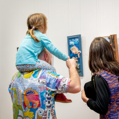 Family with child looking at artworks.