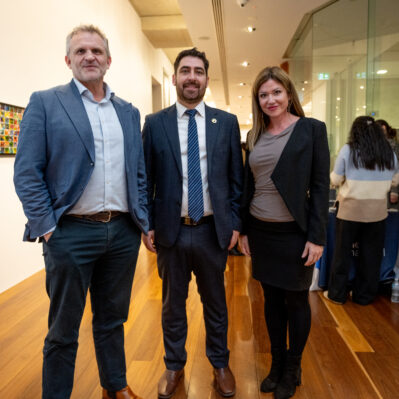 Three people standing in gallery, facing the camera.