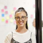Staff member smiling at camera with post it notes in background